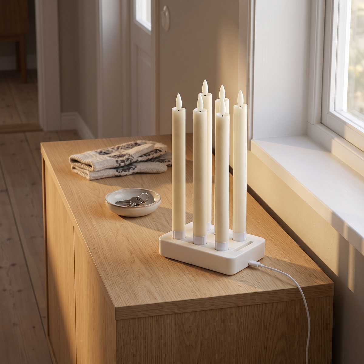 Vela's charging base holding all six taper candles on a chest of drawers in the hallway, the USB-C cable plugged in